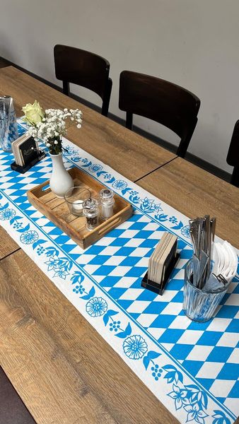 Tisch mit weiß-blauem Rautenläufer und Blumendeko